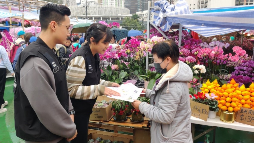 入境處特遣隊人員向年宵市場檔主派發「切勿聘用非法勞工」的宣傳單張。