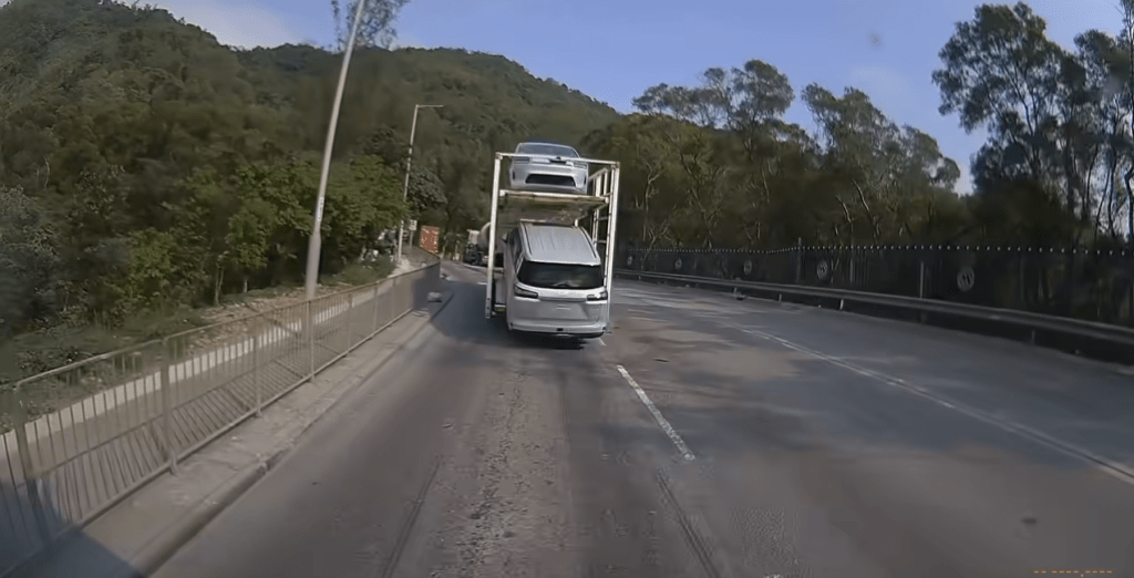 運輸車在行駛途中收慢再加速時，下層裝載的一輛私家車疑因未妥善固定，突然向後緩緩滑落。