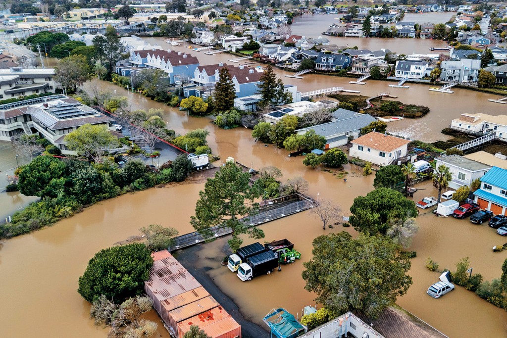 科學家指氣候變化是極端天氣日漸增加的原因，圖為上周六加州科特馬德拉溪沿岸街道被洪水淹沒。