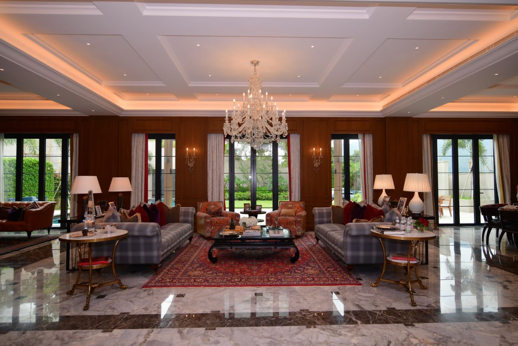 主客厅摆放水晶吊灯、格纹灰色及红色布沙发，以及黑色茶几；而主客厅及偏厅均选用复古波斯地毡， 衬托出居家唯美质感。