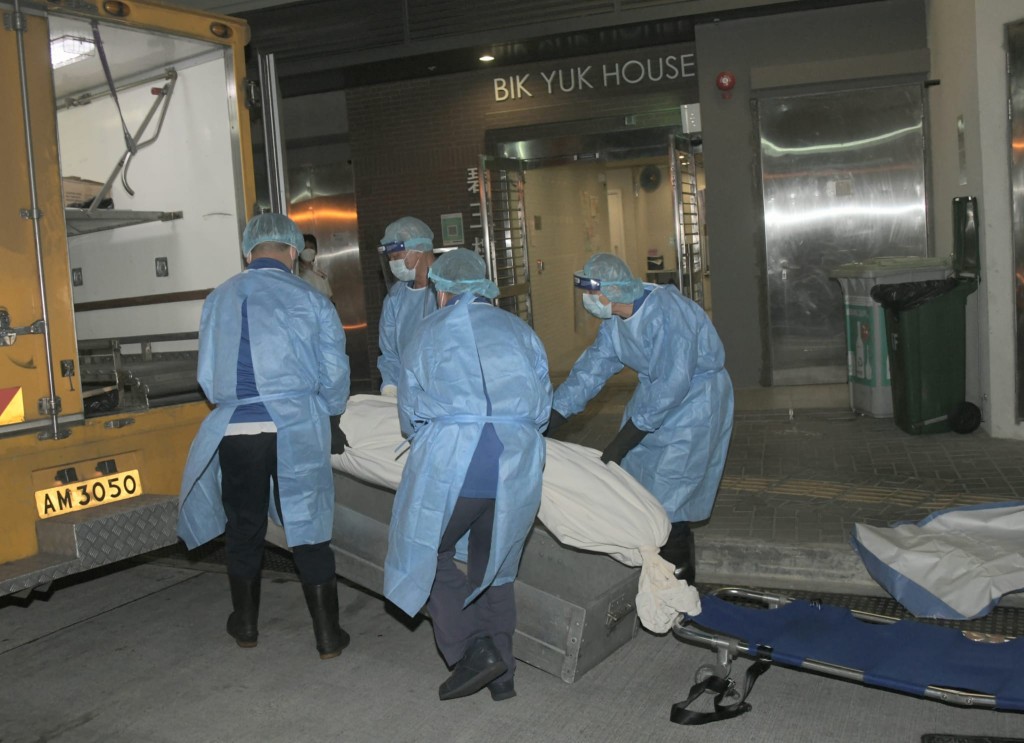 仵工將男死者的遺體抬上黑箱車。