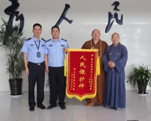 兩位身穿袈裟的大師送上寫有「人民保護神」的錦旗感謝警員破案。 網圖