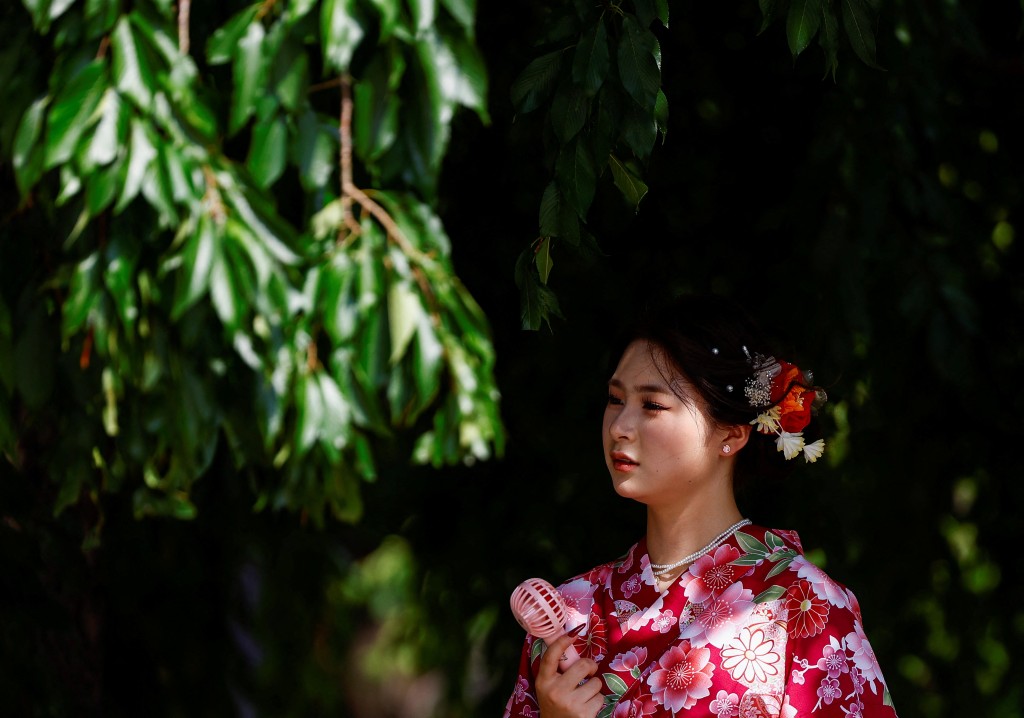 東京一名穿和服的女子在樹下以小風扇散熱。路透社