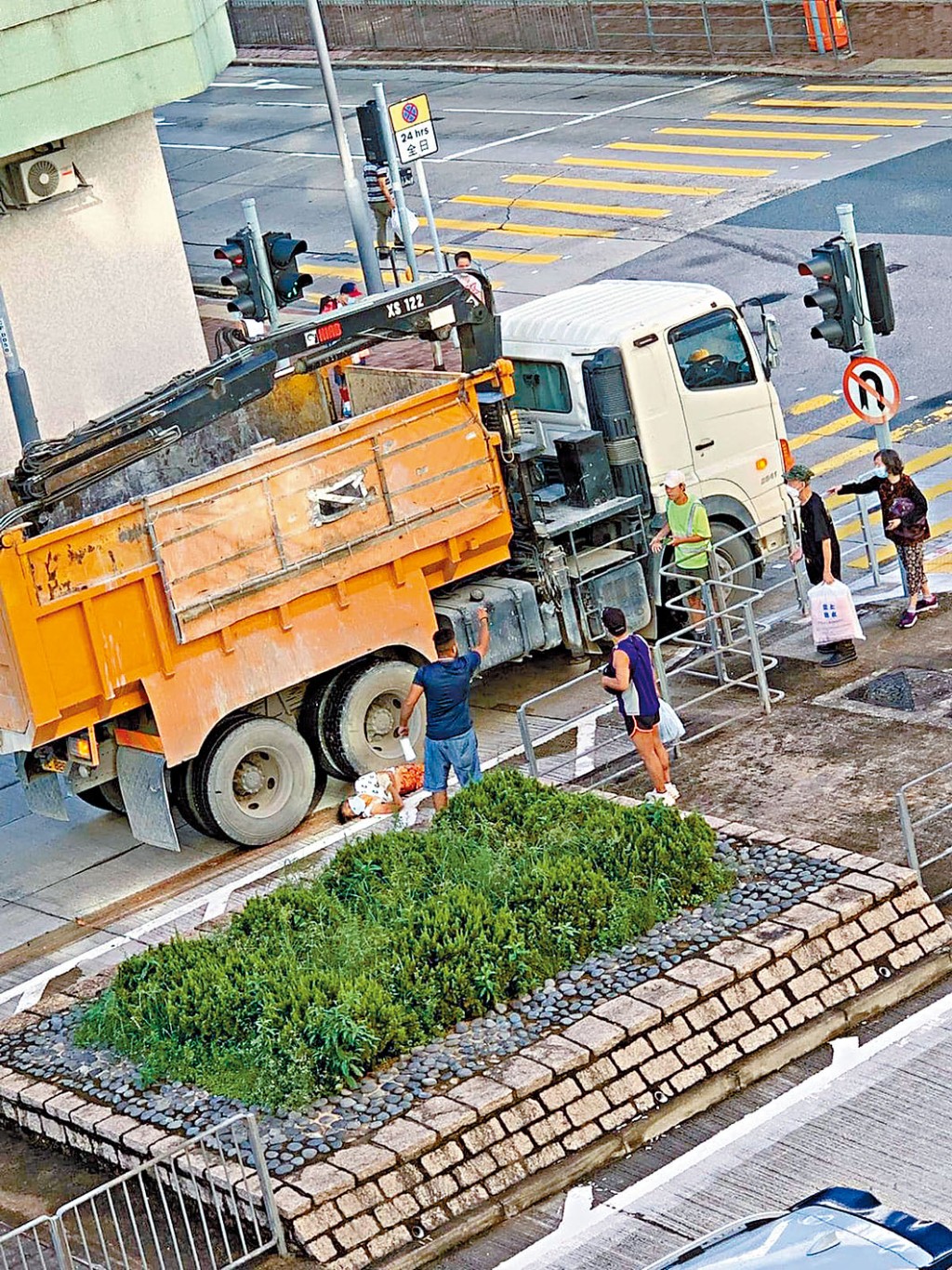過路婦捲泥頭車底遭拖行,倒卧車旁待援。
