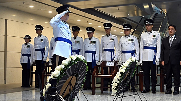 香港輔助警察隊總監梁世光於刻有殉職人員姓名的警隊紀念牆前致敬。。警務處提供