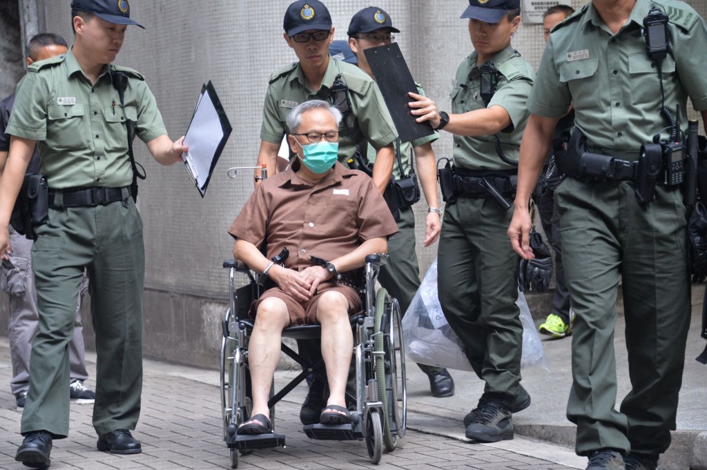 坐輪的曾蔭權由懲教人員押送。