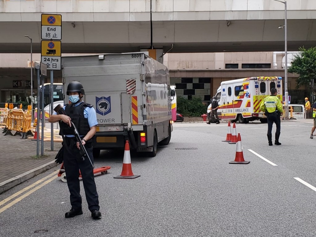 军装警员持长枪在解款车前后戒备。