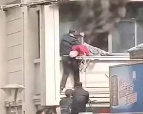 消防員搭人梯爬上二樓，將被困的一名98歲的老婦救出。 網圖
