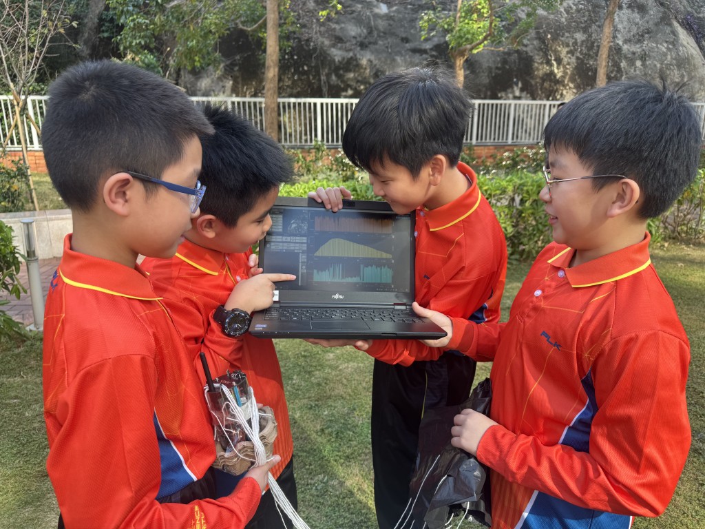 任务成功后，学生们围在电脑屏幕前，查看卫星传回的温度与高度数据图表。（图片来源：《亲子王》）