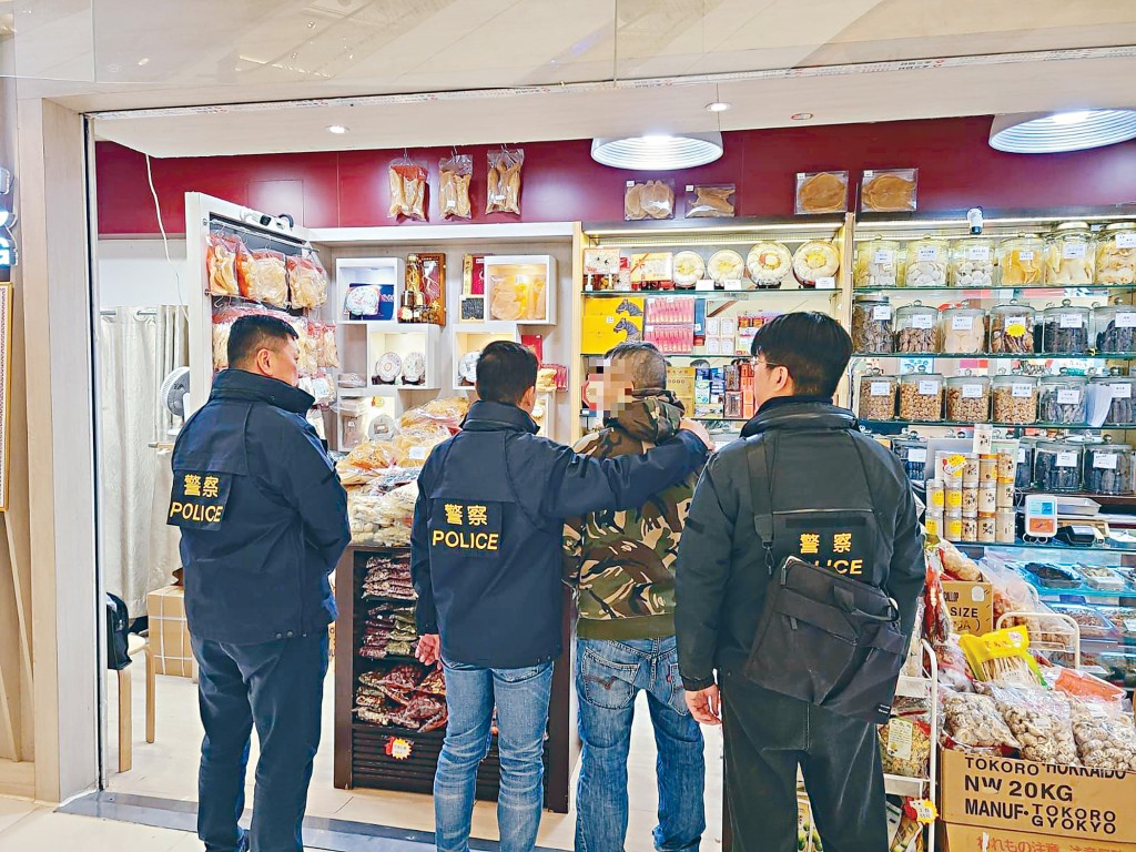 警方就涉嫌藉醫療券詐騙政府資助拘捕13人，圖為其中一名疑犯被探員押走。