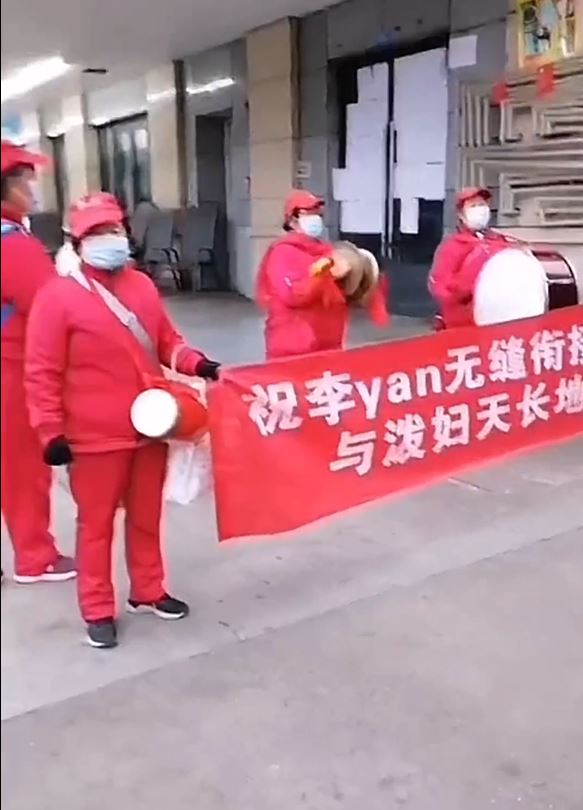 紅衣大媽鑼鼓隊在街上拉起橫額替女事主報復「渣男」。影片截圖