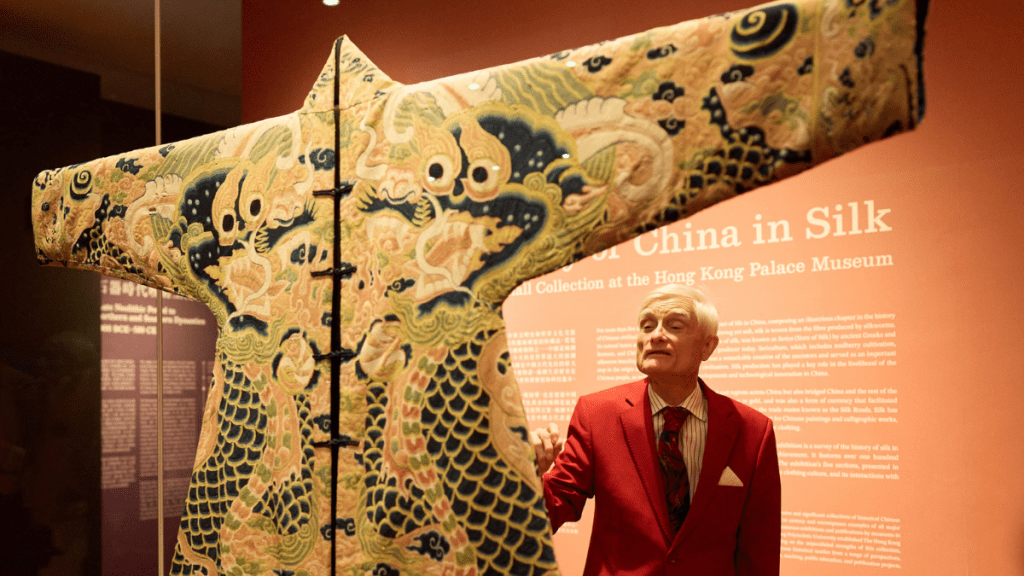 賀祈思觀賞「絲綢中國──香港故宮文化博物館賀祈思收藏」展覽中的藍色紗繡斗牛紋褂。(圖:由香港故宮文化博物館提供)