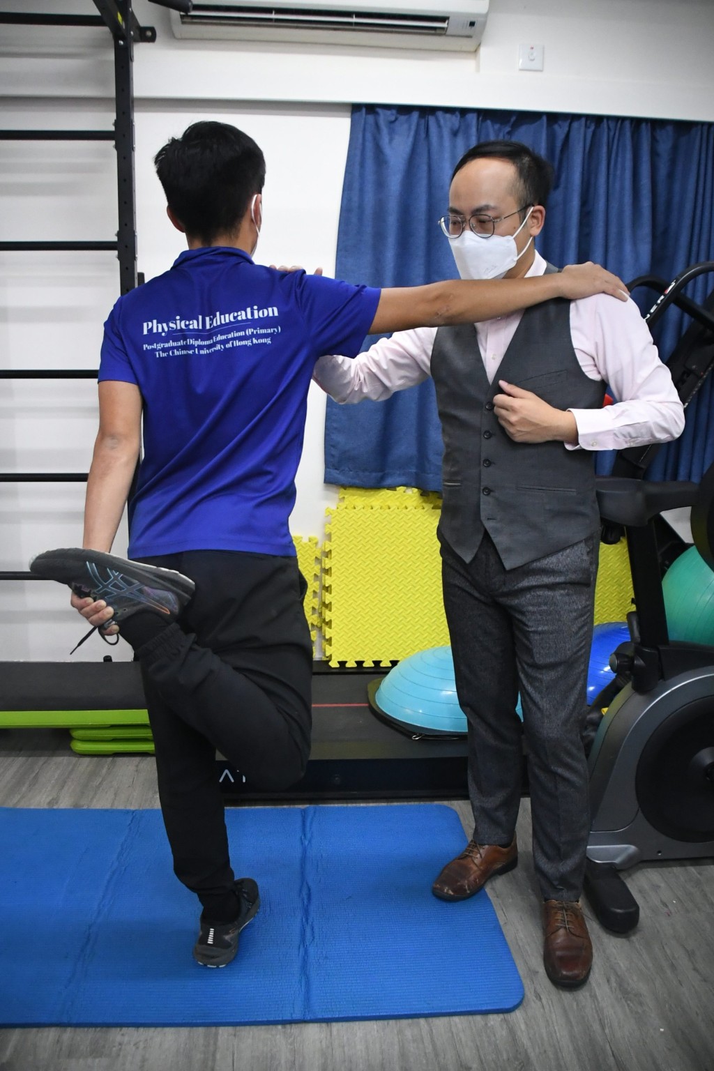 物理治療師陳嘉渝(右)指四頭肌熱身有助放鬆肌肉。 本報記者攝