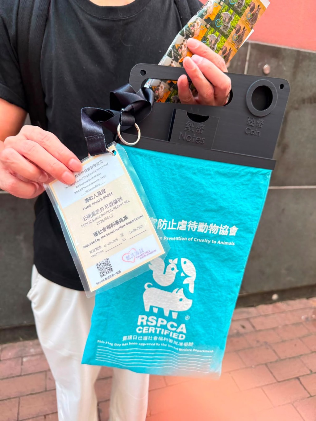 假賣旗人士所持的旗袋為淺藍色，上面印有「防止虐待動物協會RSPCA CERTIFIED」。