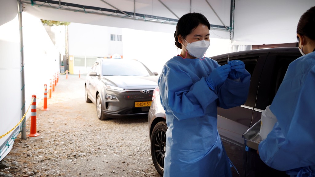 新冠疫情期间，韩国护士为车上的人接种新冠疫苗。 路透社