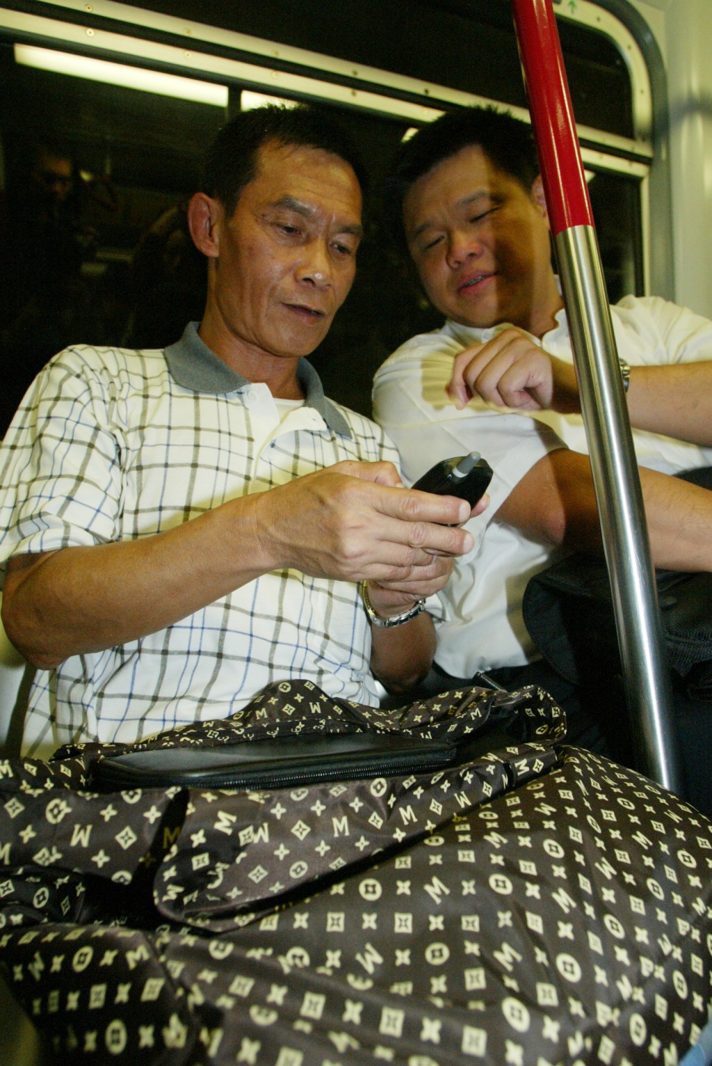 欧阳炳强（左）学习使用七十年代仍未面世的手机。资料图片