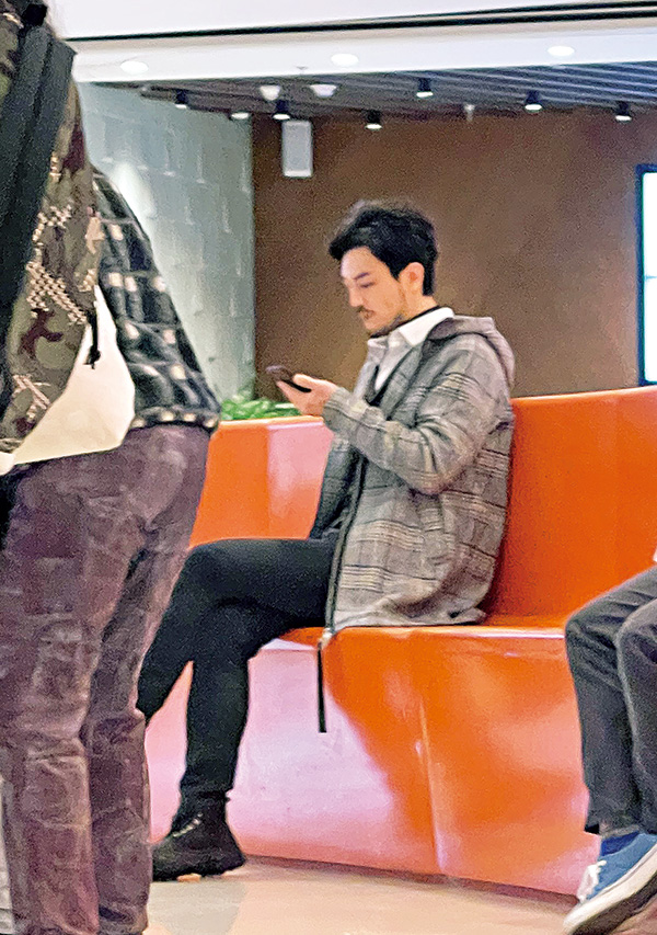 坐在溜冰場旁邊的栢天男，專心地看着電話，縱使很多人行過身邊，他依然不受影響。