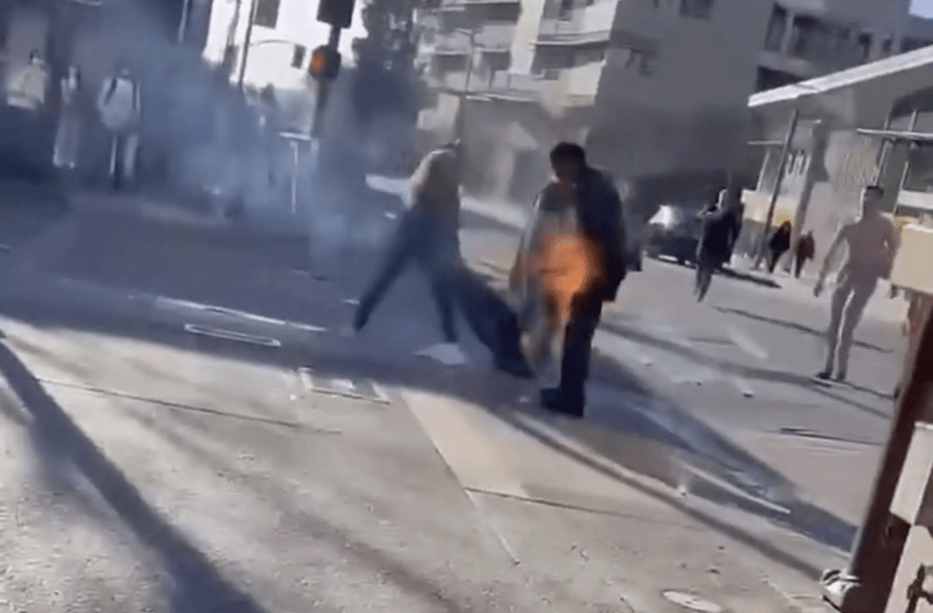一名女子用外套拍打他，试图救火。