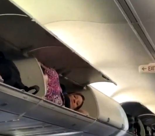 美国廉航西南航空有女乘客爬上行李架当做卧铺。