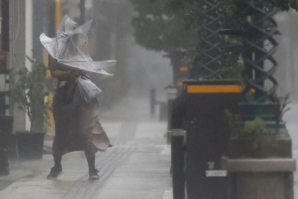 日本南部宮崎縣一名女子周日在颱風「南瑪都」吹襲下，舉傘冒着風雨前行。AP