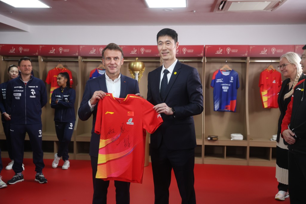 馬克龍接受中國隊贈送的球衣。 新華社
