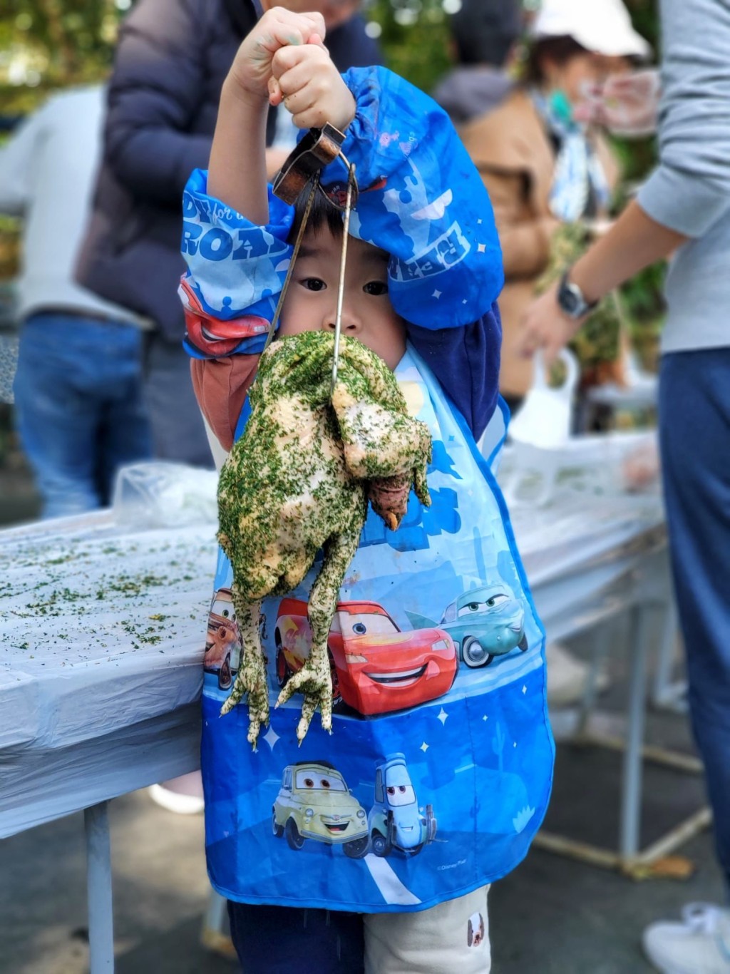 職員介紹醃雞步驟後，小朋友用農場的香草醃雞，親子合作將雞鈎在燒雞鈎上，然後掛在烤爐內。（圖片來源：受訪者提供）