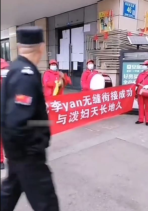 红衣大妈锣鼓队在街上拉起横额替女事主报复「渣男」，保安经过亦没有阻止。影片截图