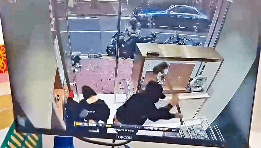 一名劫匪以大鐵錘扑碎飾櫃玻璃，繼而與同黨極速取走約30隻名錶。