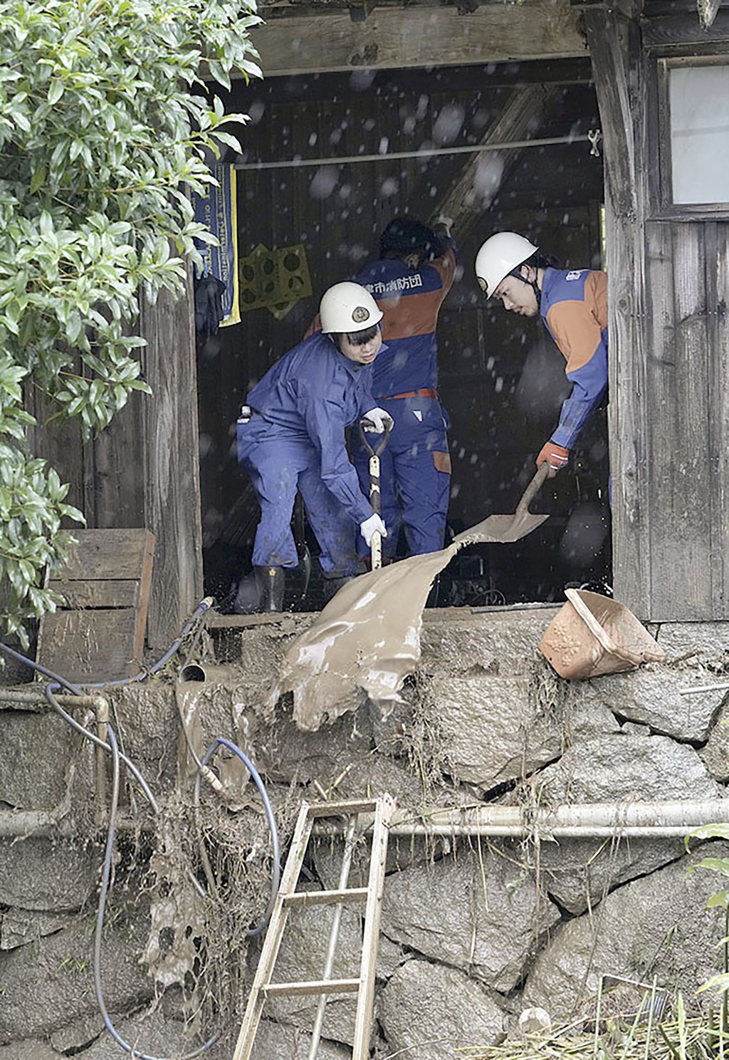 日本南部佐賀縣唐津市，消防隊員從山泥傾瀉受損的房屋中挖出泥漿。AP