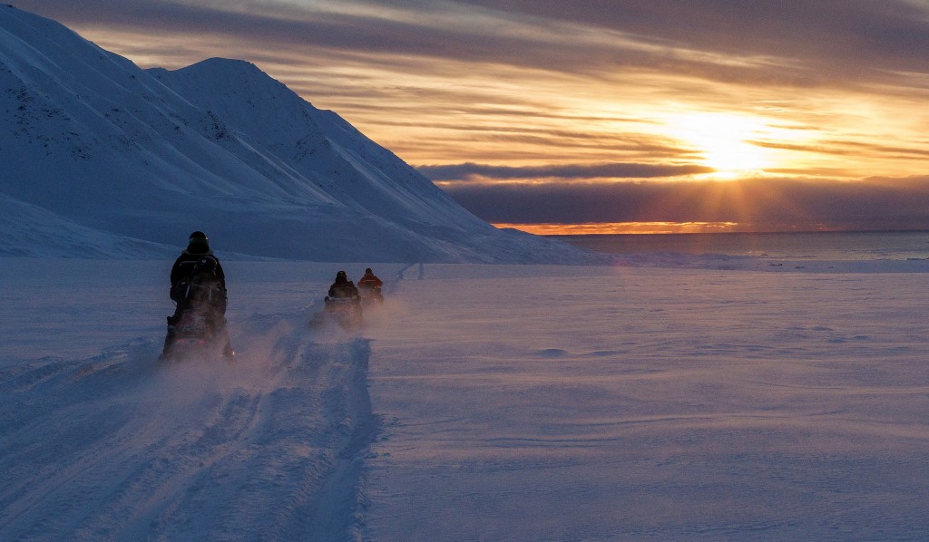 科学家在日落时分驾驶雪地电单车穿越北极。路透社