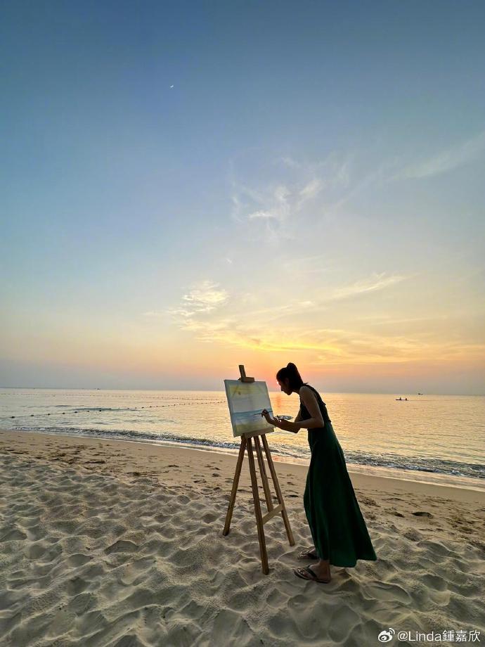 鍾嘉欣在沙灘上觀看日落並繪畫美景時刻。