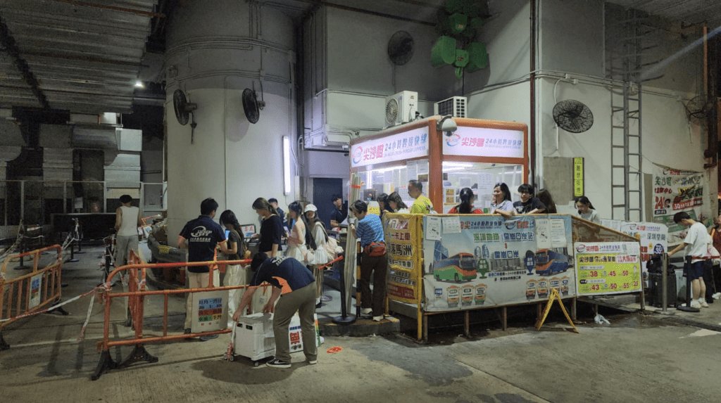 總站內可見多輛跨境旅遊巴停泊候命，職員在櫃位為旅客辦理購票及登車安排。黎志偉攝