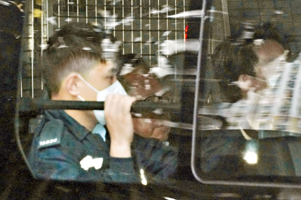 何俊仁由警車押送出庭。