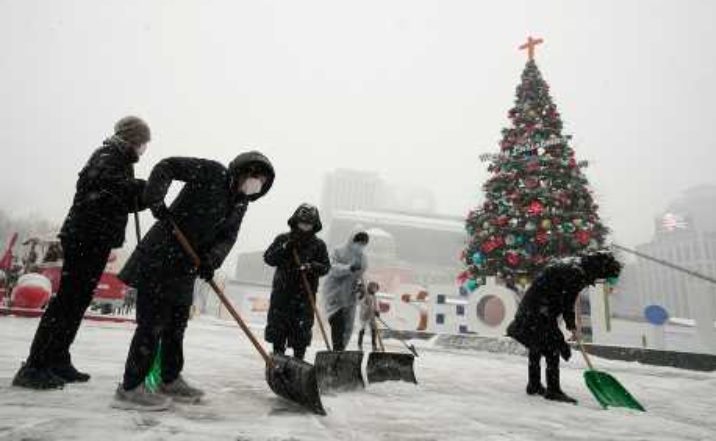 首尔上周四大雪，工人清理市政厅行人道积雪。美联社