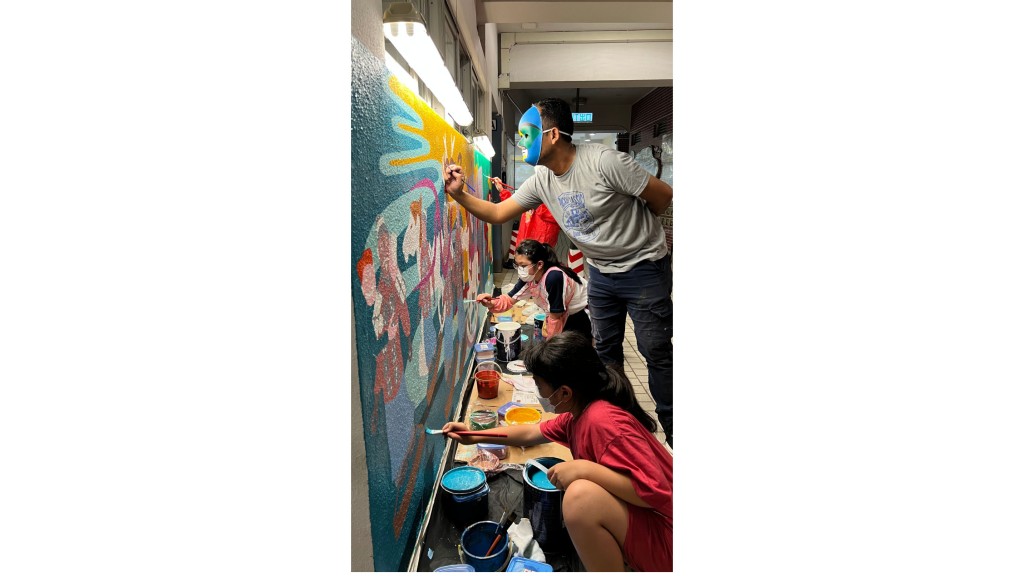 小學生與蒙面藝術家一起繪畫牆壁。