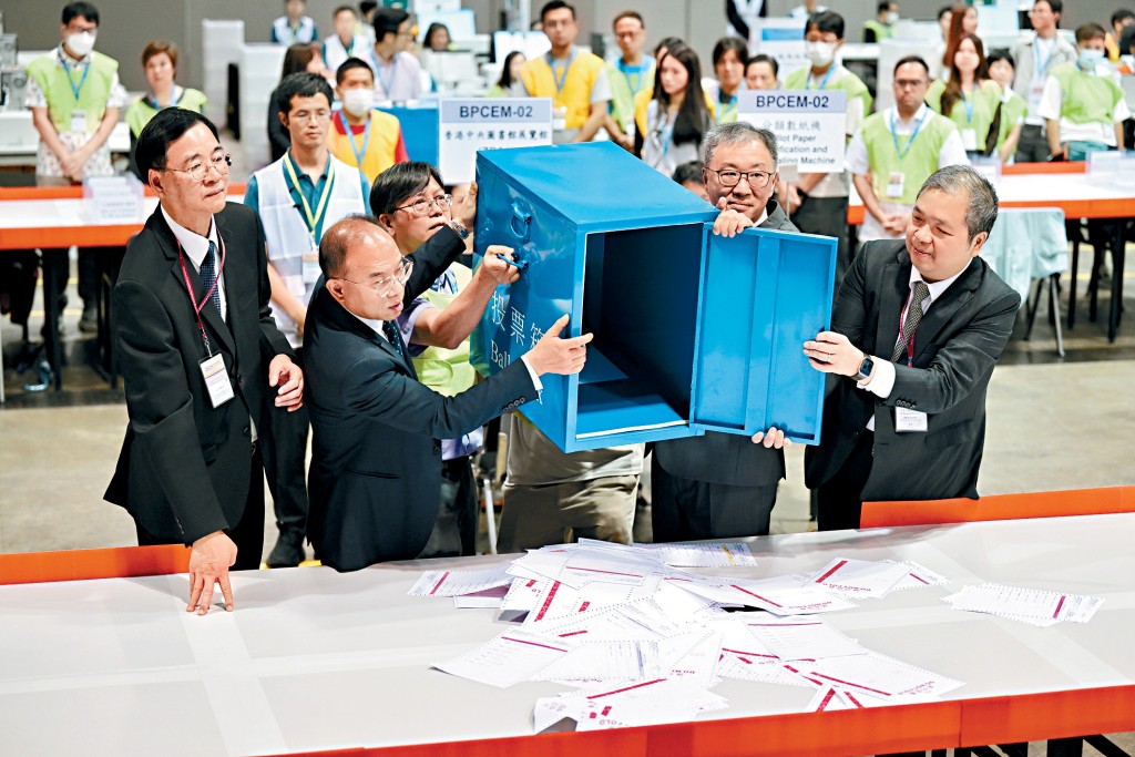 陸啟康及曾國衞等開啟第一個送抵會展中央點票站的票箱，倒出選票。