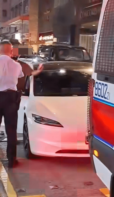 外籍男情緒失控,在其白色Tesla私家車旁邊不斷用不純正的廣東話向警員爆粗辱罵。 外籍男情緒失控,在其白色Tesla私家車旁邊不斷用不純正的廣東話向警員爆粗辱罵。