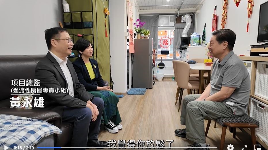 何永賢(左二)探望剛搬到元朗江夏圍村過渡性房屋的居民譚先生。短片截圖