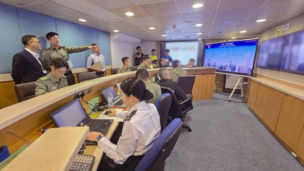 懲教署署長黃國興(後排左一)在演習期間巡視在赤柱的中央控制中心,並聽取懲教署署理助理署長(行動)洪嘉諾(後排左二)匯報應變演習情況。 懲教署署長黃國興(後排左一)在演習期間巡視在赤柱的中央控制中心,並聽取懲教署署理助理署長(行動)洪嘉諾(後排左二)匯報應變演習情況。