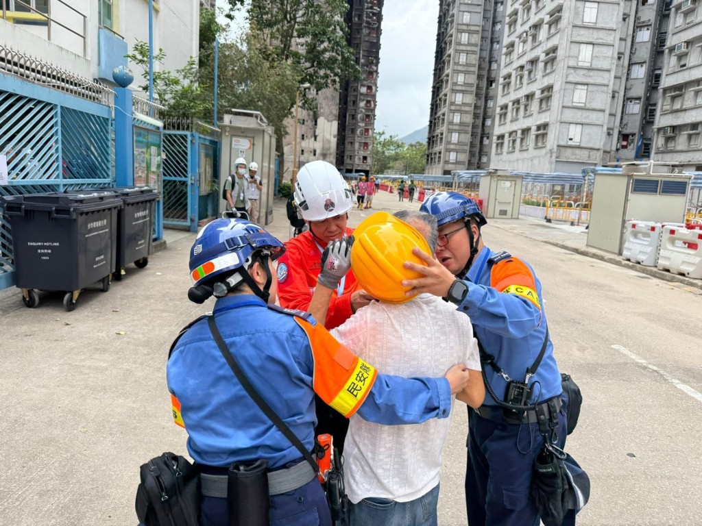 民安隊陪伴居民上樓前，因應需要會為長者戴上防護裝備。(民安處提供圖片)