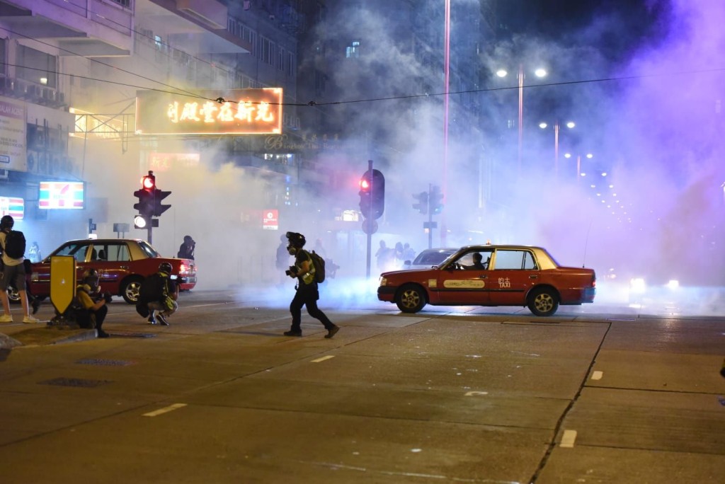 警方發射催淚彈時，現場仍有不少汽車在路中心。