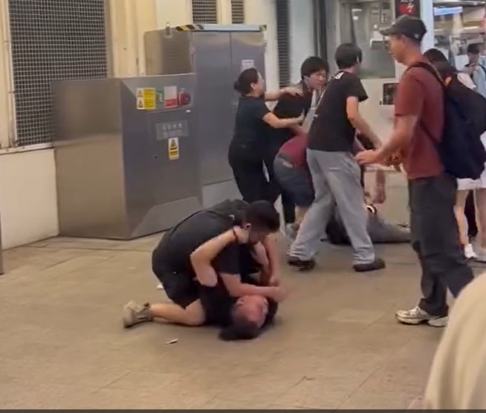 短褲男「壓頸」控制對方、牛仔褲男動彈不得、頭部「面色通紅」、表情痛楚。