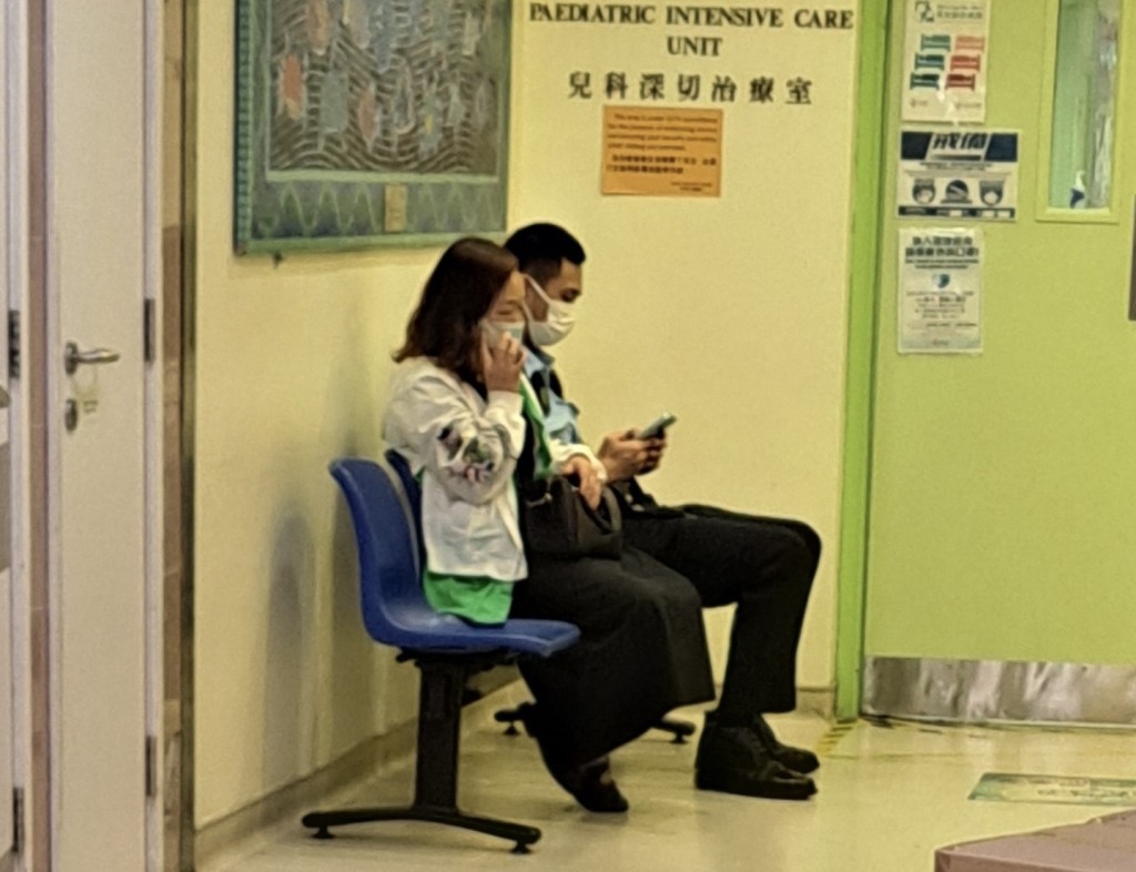 男童的母亲沈女士（白衫）坐在医院儿童深切治疗部门外。