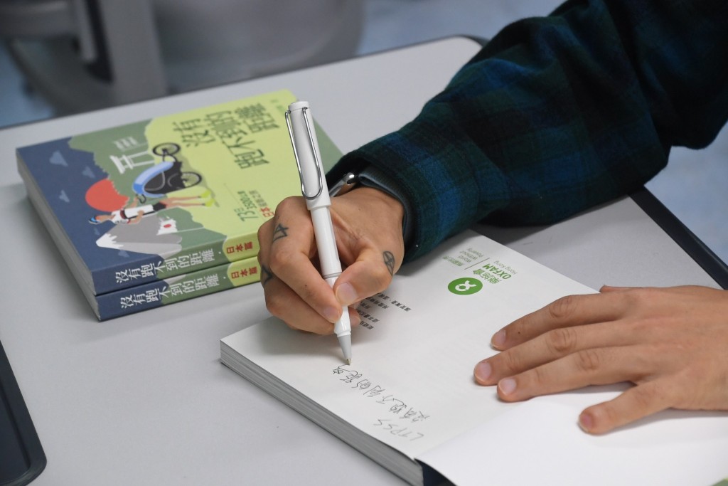 黃俊橋在個人著作上簽名，送贈學生。 本報記者攝