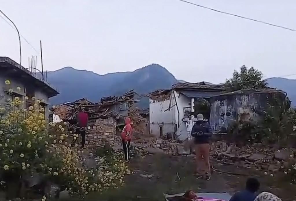 村民站在地震受损的房屋前。 AP