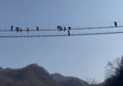 龙潭大峡谷景区有游客在玩网红铁索桥时，意外跌出，在半空吊吊揈。影片截图
