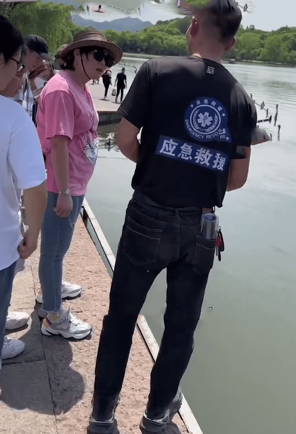身穿「应急救援」的男子与游客在商议打捞手机的费用。