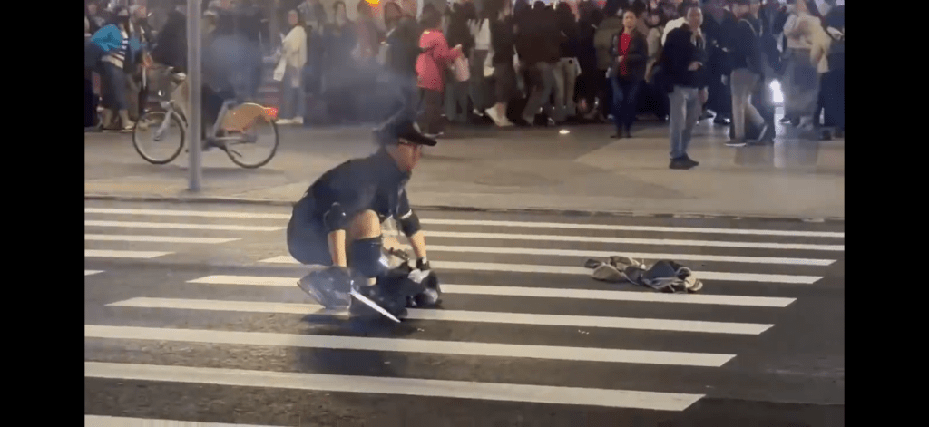 張文在馬路中心丟煙霧彈後，從袋中取出長刀。