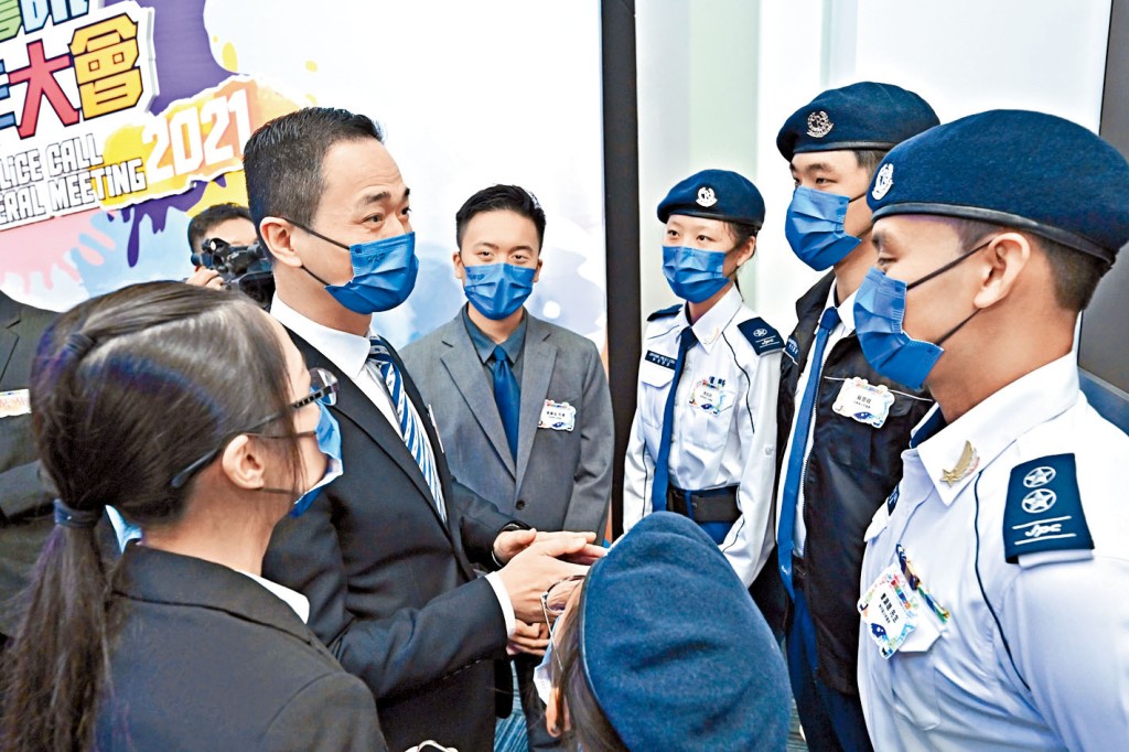 警務處助理處長(公共關係)陳東(左二)與穿着少年警訊新制服的深資領袖曹灝聰(右)交談。