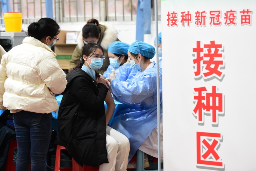 在安徽省合肥市一个新冠疫苗加强针接种点，医护人员为学生和教职员接种。 新华社